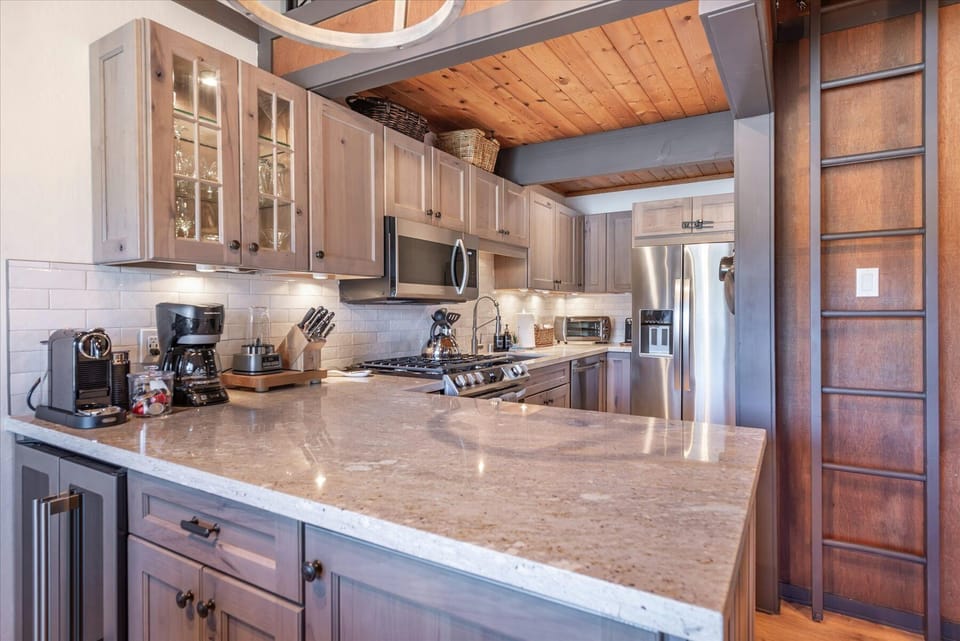 Your fully equipped kitchen features granite counters, stainless appliances, and warm wood beams overhead—perfect for creating memorable meals together.