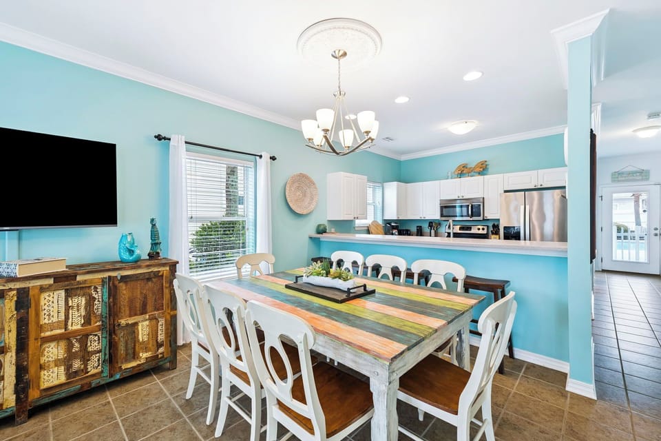 Gather around your coastal dining table with loved ones, where turquoise walls and white furnishings create a breezy beach house atmosphere.