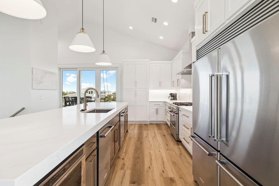You'll love preparing meals in this stunning chef's kitchen with premium stainless appliances, pristine white countertops, and natural light streaming through waterfront windows.