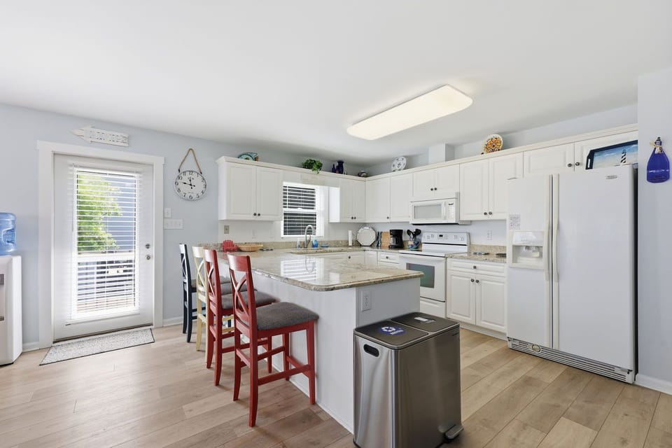 Your fully-equipped kitchen features bright white cabinets, granite counters, and a central island perfect for meal prep or casual dining with friends and family.