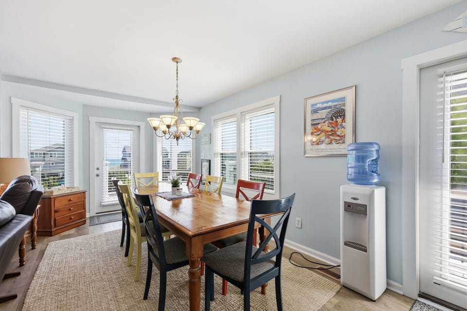 Gather for meals at your welcoming dining table, surrounded by soft blue walls and coastal charm, with ocean views peeking through every window.