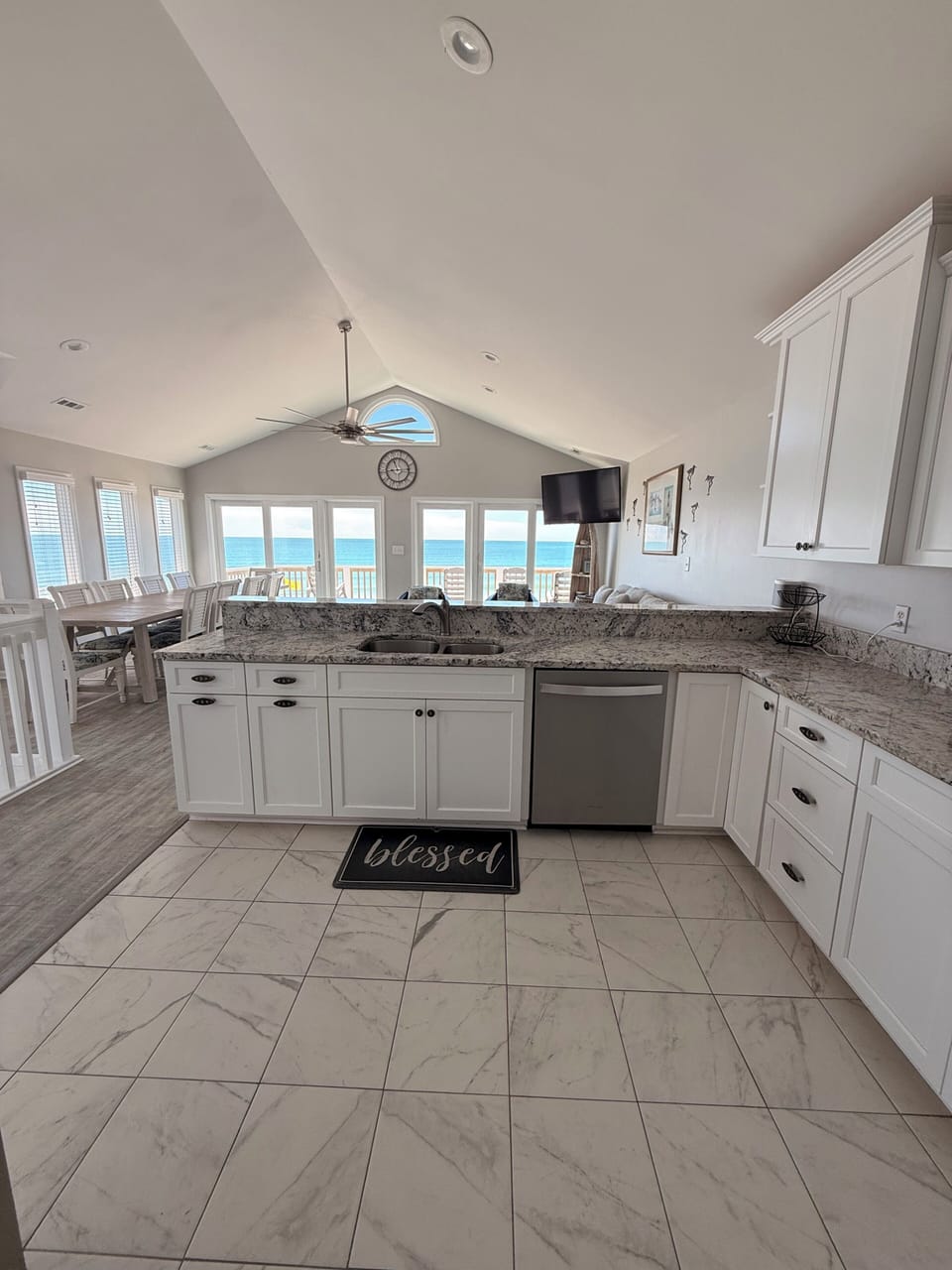 Bright, modern kitchen bathed in natural light, featuring elegant marble-look tile backsplash, exposed beam character, and ample storage for your culinary adventures.