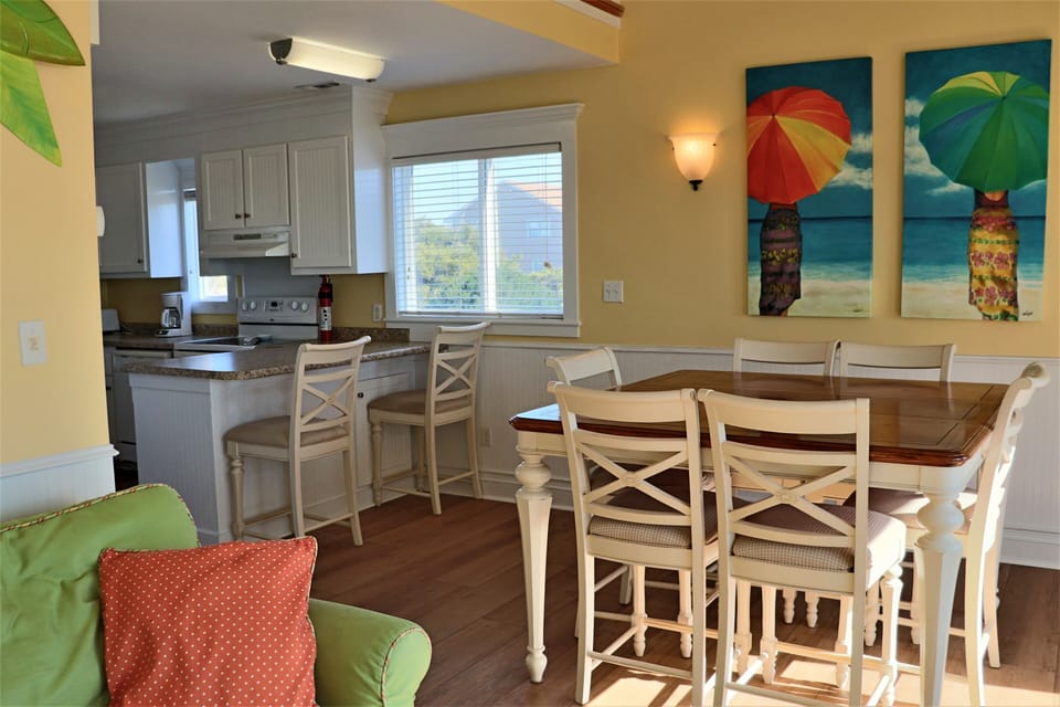 Gather around your bright dining space where cheerful beach art and warm colors create the perfect backdrop for memorable meals together.