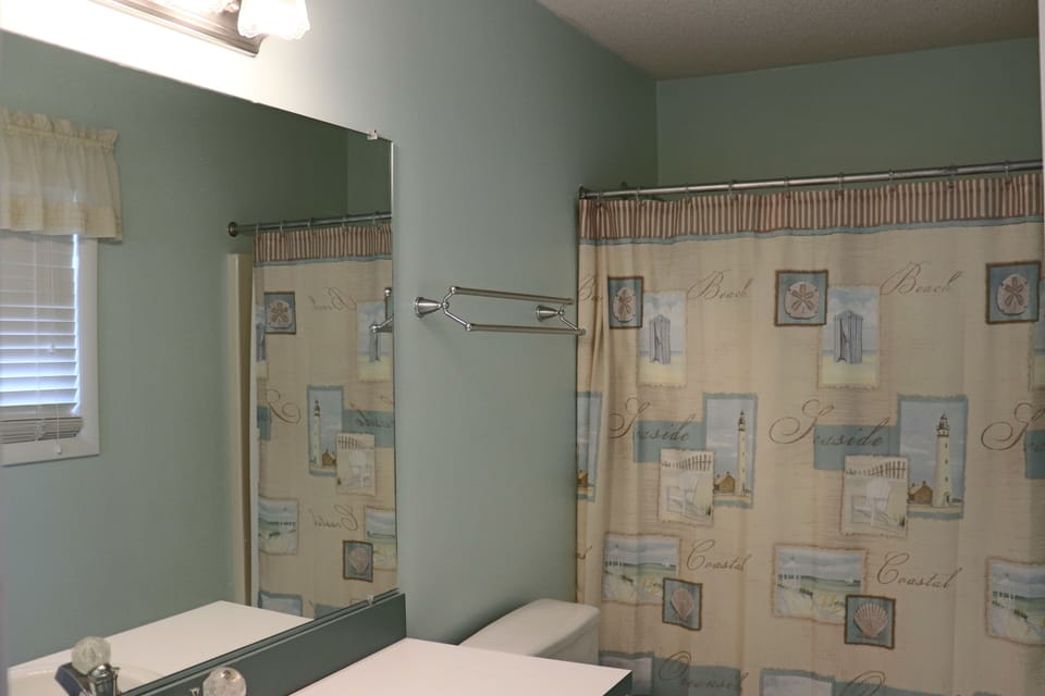 Step into your private coastal-themed bathroom featuring beach-inspired decor and a refreshing shower to start each vacation day renewed.
