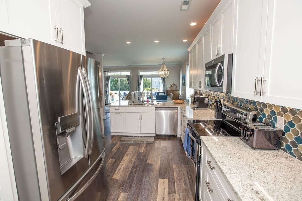 Prepare delicious meals in your modern galley kitchen, featuring stainless steel appliances, granite countertops, and stylish mosaic backsplash.
