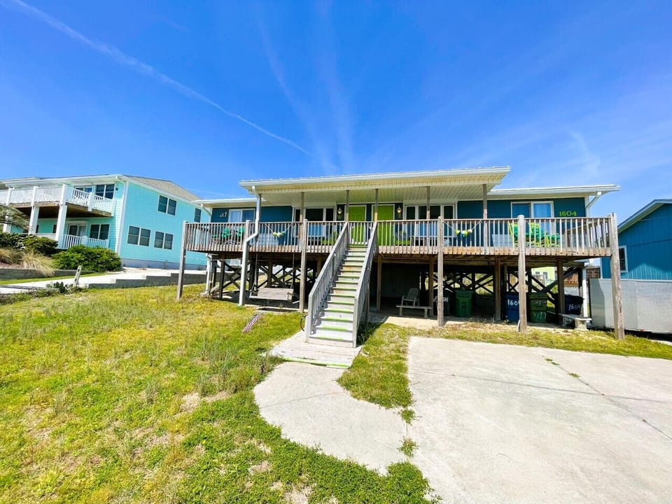 Colorful beach houses on stilts with convenient parking and easy stair access create the perfect coastal getaway setting.
