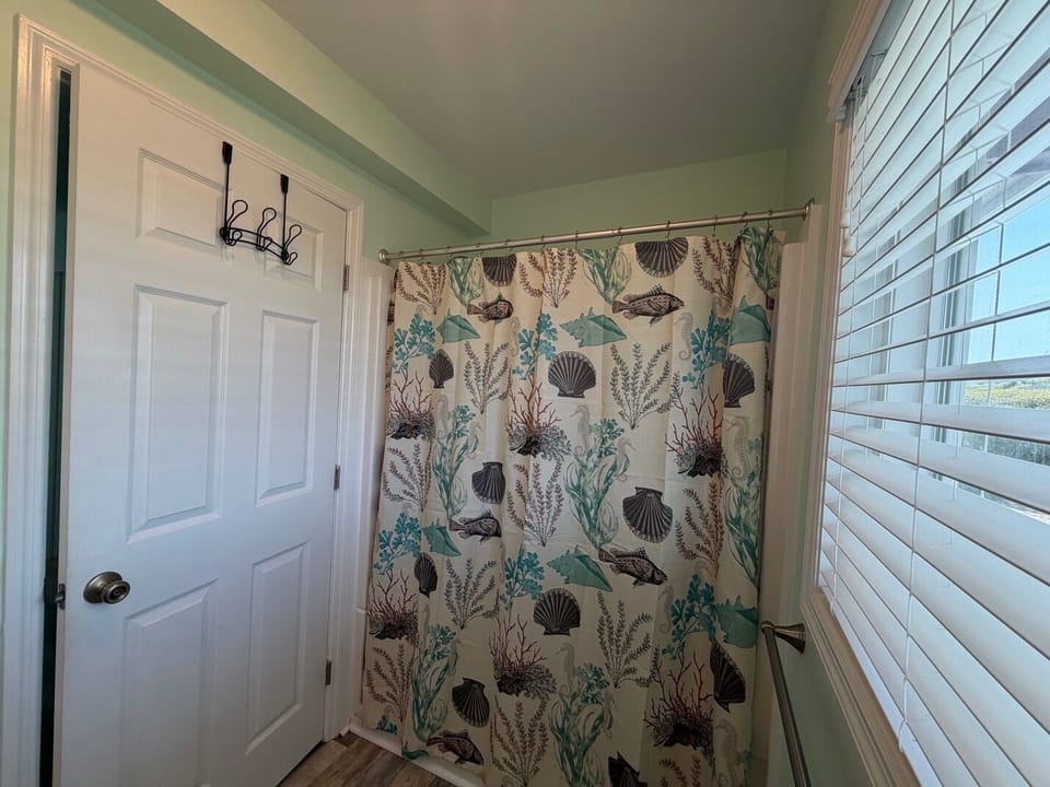 Your private bathroom features a charming ocean-themed shower curtain that brings coastal vibes to your daily routine.