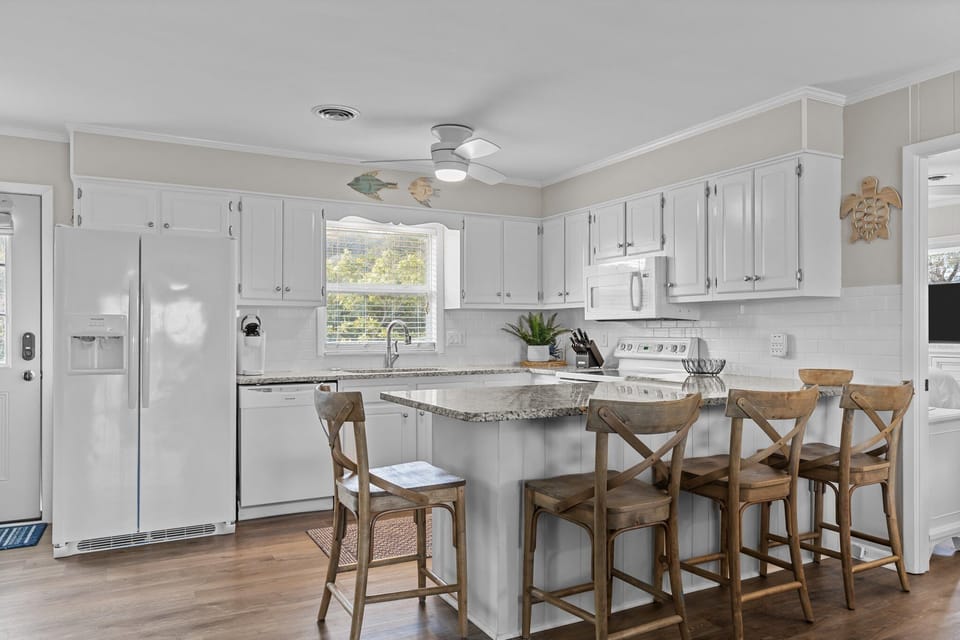 You'll love cooking in this bright, fully-equipped kitchen with granite counters, coastal touches, and a welcoming breakfast bar for morning coffee together.