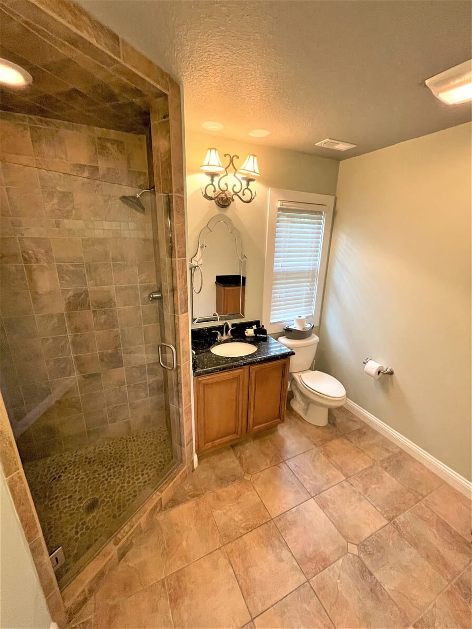 Your spacious bathroom features elegant stone tile, a glass-enclosed shower, and warm lighting that creates a spa-like retreat for your daily routine.
