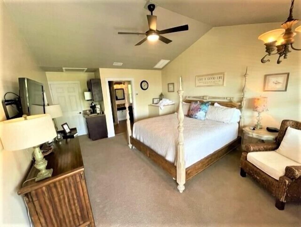 Unwind in your spacious master bedroom featuring a charming four-poster bed and cozy wicker seating area perfect for quiet moments.
