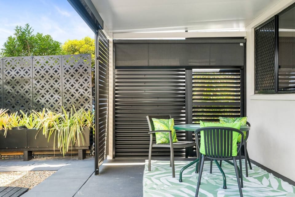 Outdoor patio area with dining table, sunlounger and tool shed. 