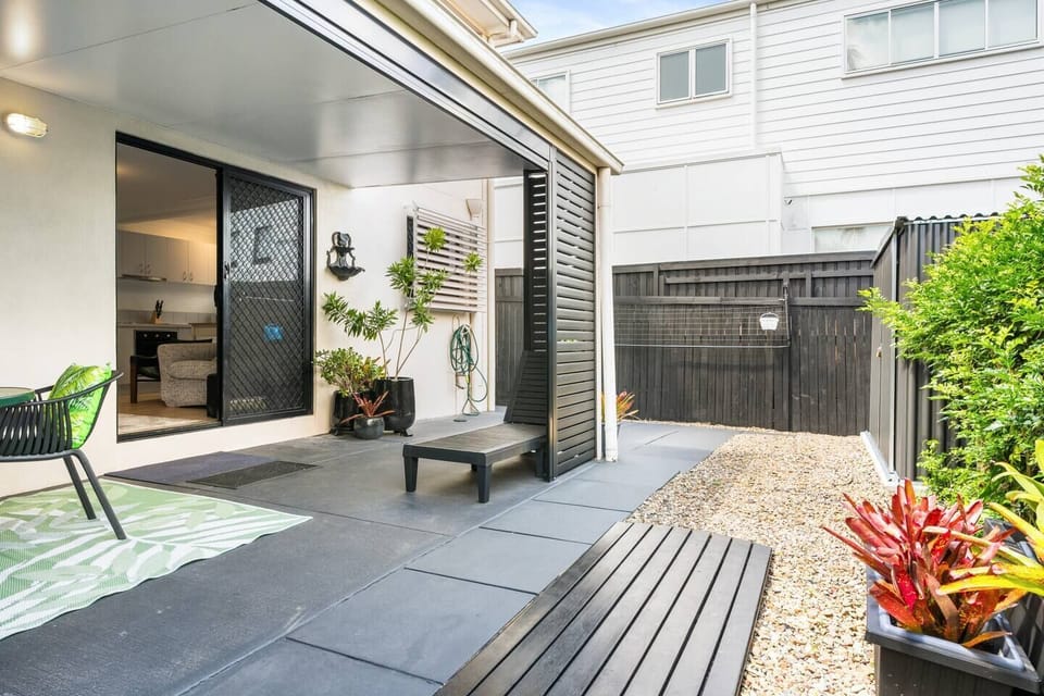 Outdoor patio area with dining table, sunlounger and tool shed. 
