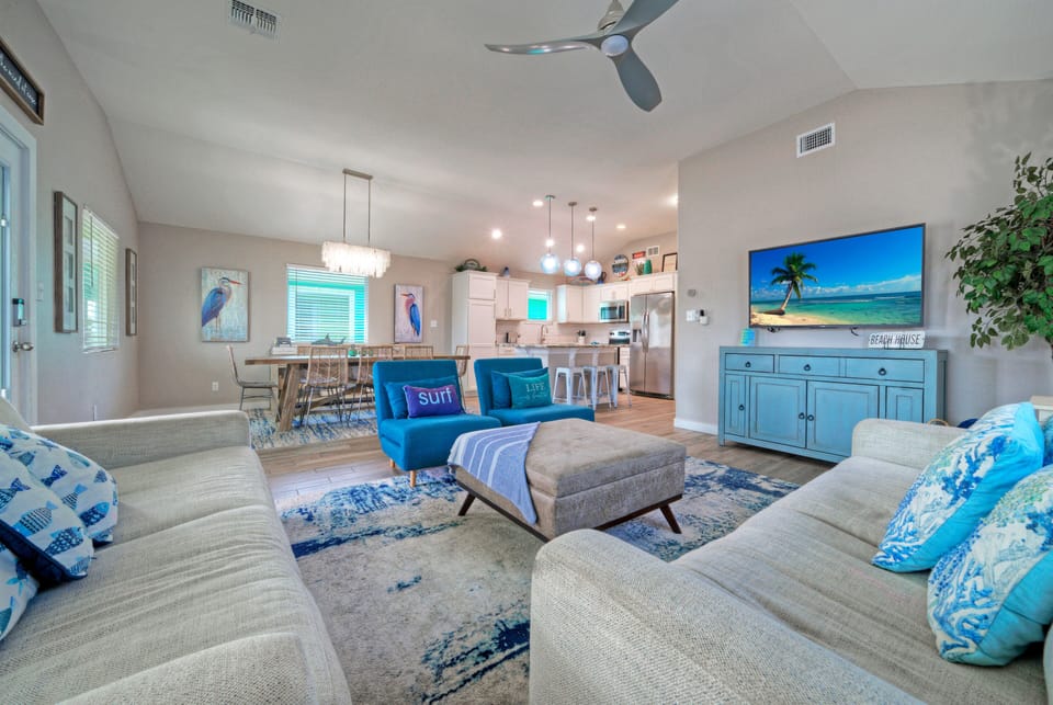 Bright open-concept living area with comfortable seating, coastal décor, and seamless flow to the kitchen and dining space.