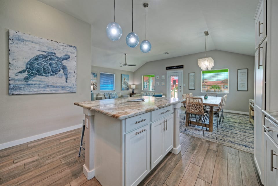 Fully equipped kitchen with granite island, bar seating, and stylish coastal lighting.