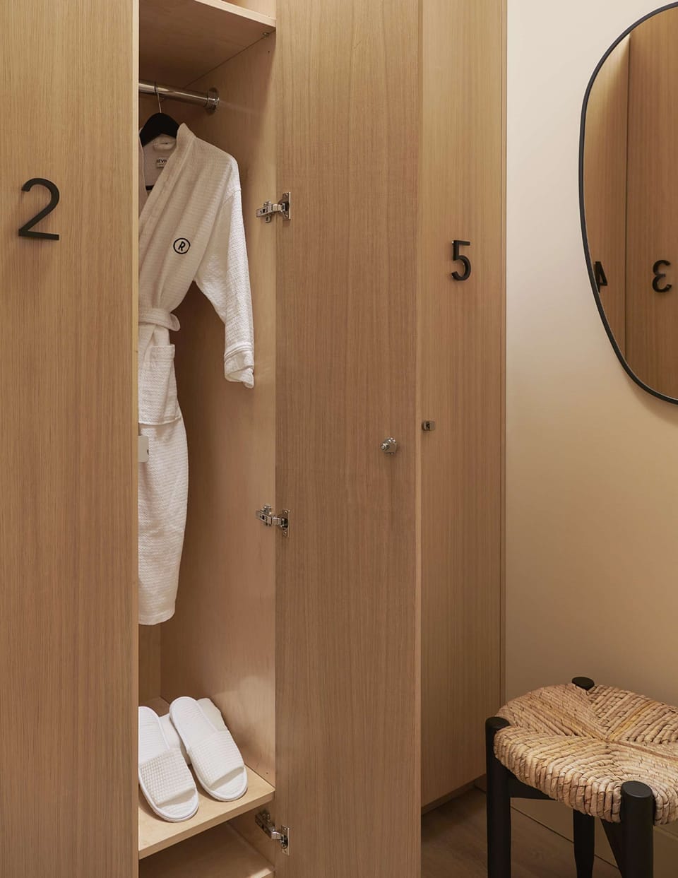 Open lockers with hanging robes, slippers, stool, and oval mirror