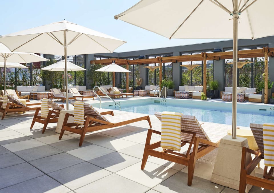 Poolside benches, planters, and patterned stools along tiled deck
