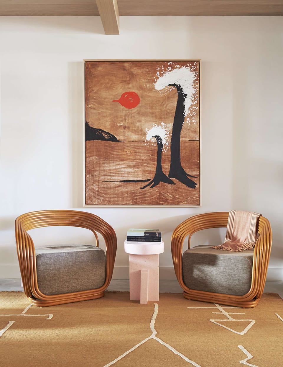 Paired lounge chairs beneath framed painting with textured tones
