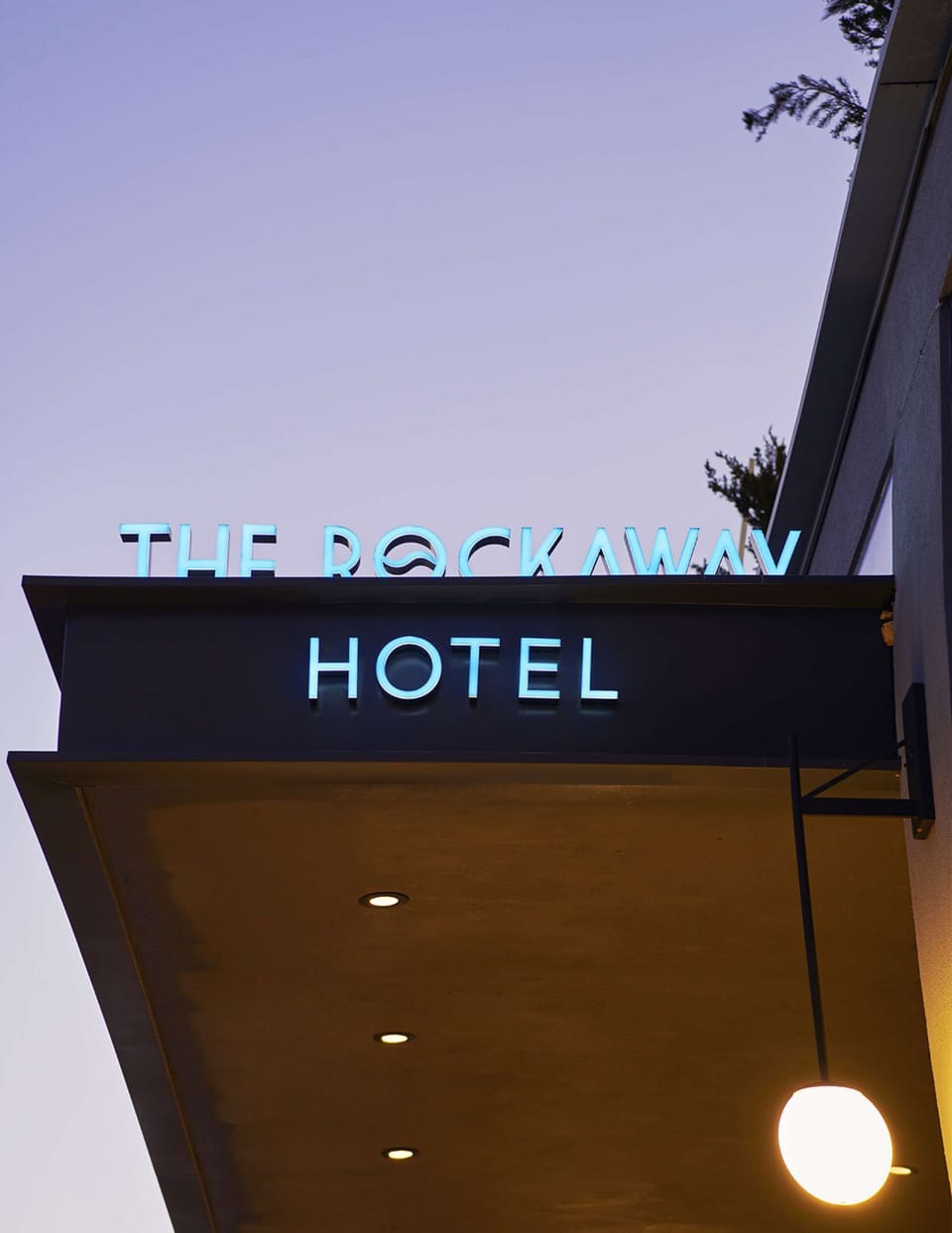 Property Glowing sign above entry canopy against dusk sky