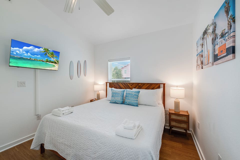 Unwind in your cozy bedroom with modern furnishings, tropical artwork, and fluffy towels ready for your arrival.