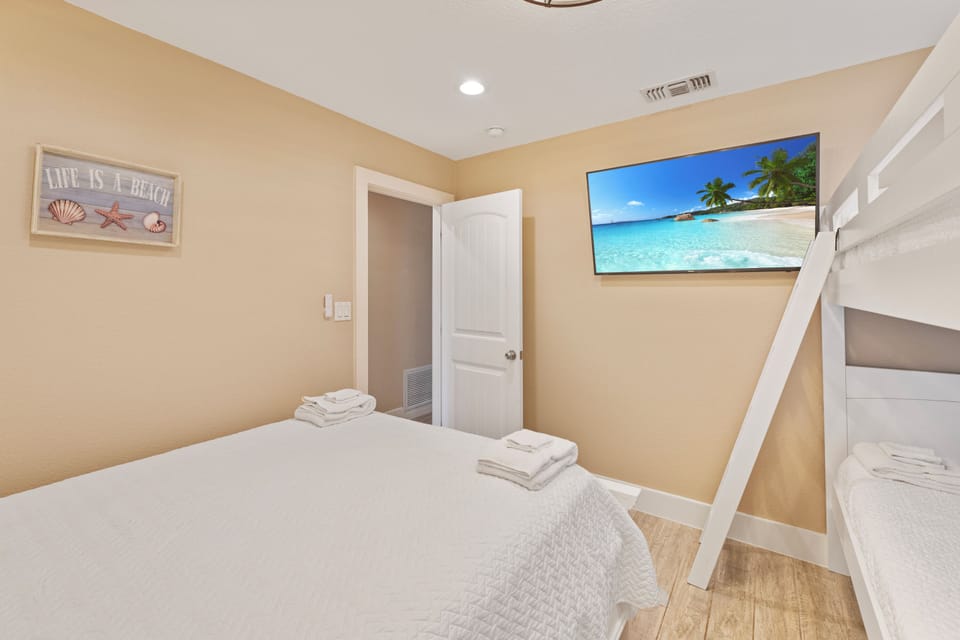 Unwind in your cozy bedroom featuring a comfortable queen bed, bunk beds for extra guests, and tropical beach decor that sets the vacation mood.