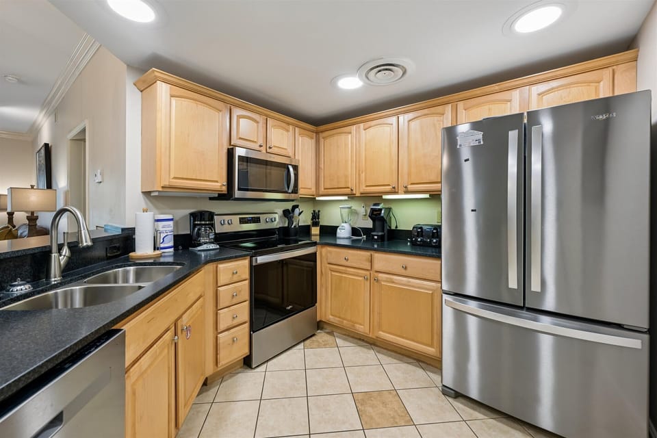 Your fully equipped kitchen features warm wood cabinets, granite counters, and stainless appliances - perfect for preparing delicious meals together.