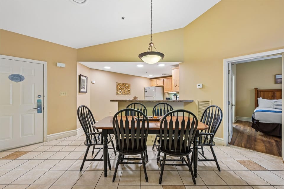 Gather around your spacious dining table for six, where warm golden walls and elegant pendant lighting create the perfect atmosphere for memorable meals together.