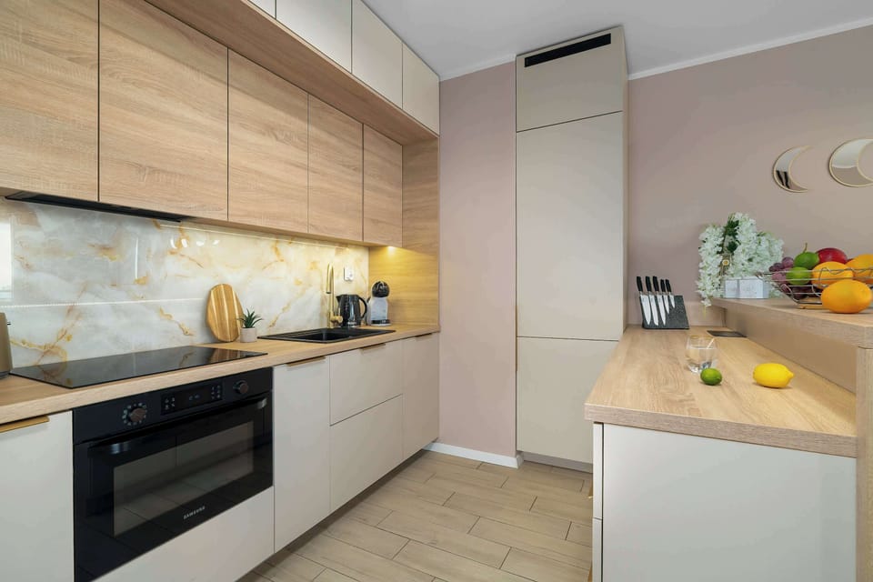 A contemporary kitchenette layout highlights light wood upper cabinetry complemented by clean white lower units and built-in appliances.