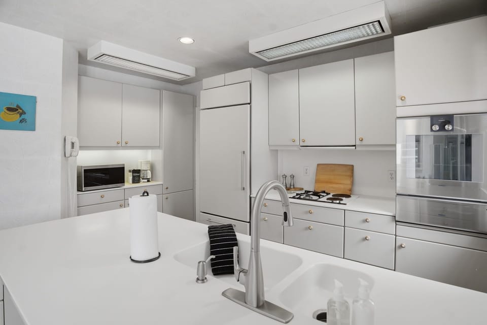Your spacious kitchen invites culinary adventures with sleek white cabinetry, modern appliances, and pristine countertops perfect for meal prep.
