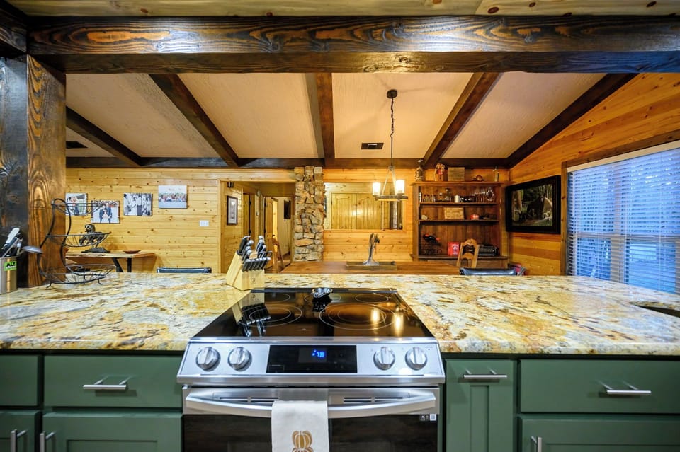 Cook in your rustic kitchen with granite counters, exposed beams, and cozy stone fireplace creating the perfect mountain retreat atmosphere.