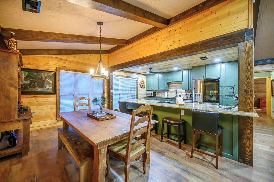 Gather around the rustic dining table where warm wood beams frame your mountain retreat moments, while the fully-equipped kitchen awaits your culinary adventures.