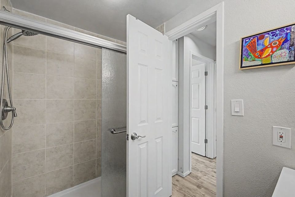 Bathroom featuring a tiled shower with sliding glass doors and colorful wall art.