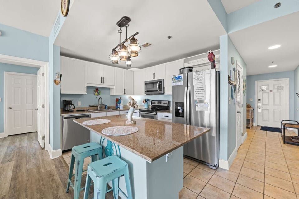 Spacious kitchen with granite countertops, stainless steel appliances, and bar seating for casual dining.