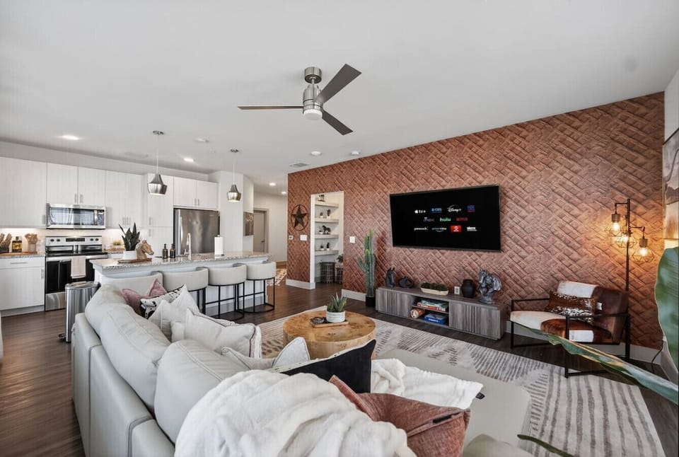 Living area: Bright open living space with stylish Texas-inspired accent wall, cozy seating, and Smart TV—perfect for relaxing or gathering with your group.