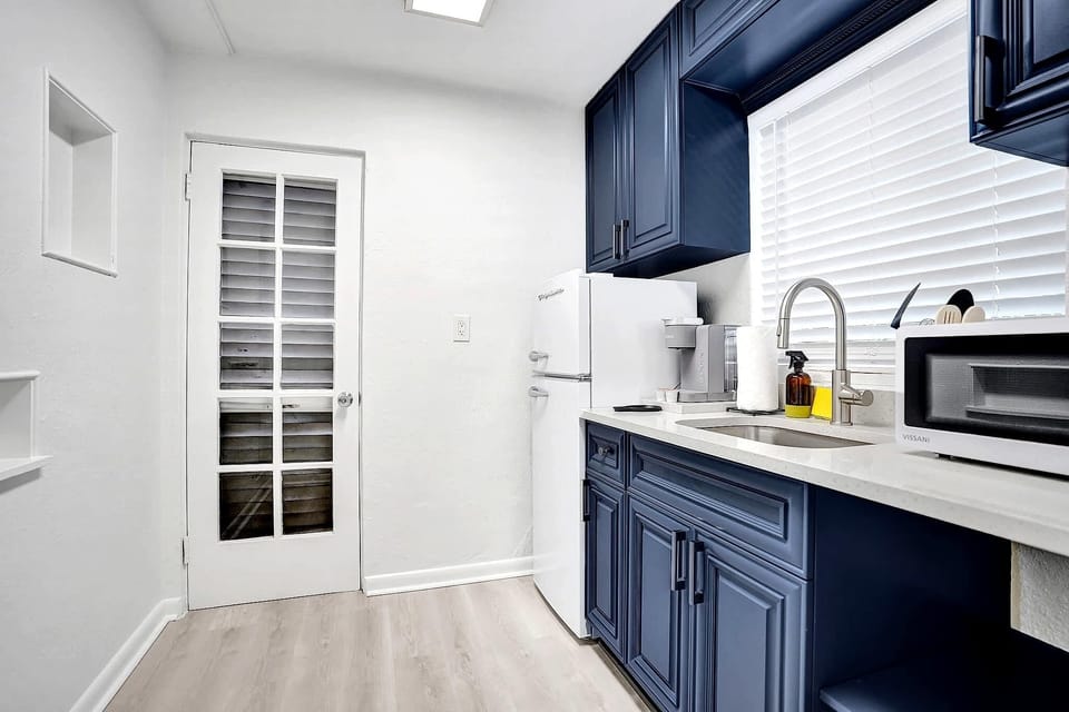 Full kitchenette with navy cabinets and wine fridge