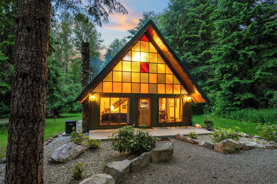 Side view of the cabin showcasing stone landscaping, warm evening ambiance, and private wooded lot