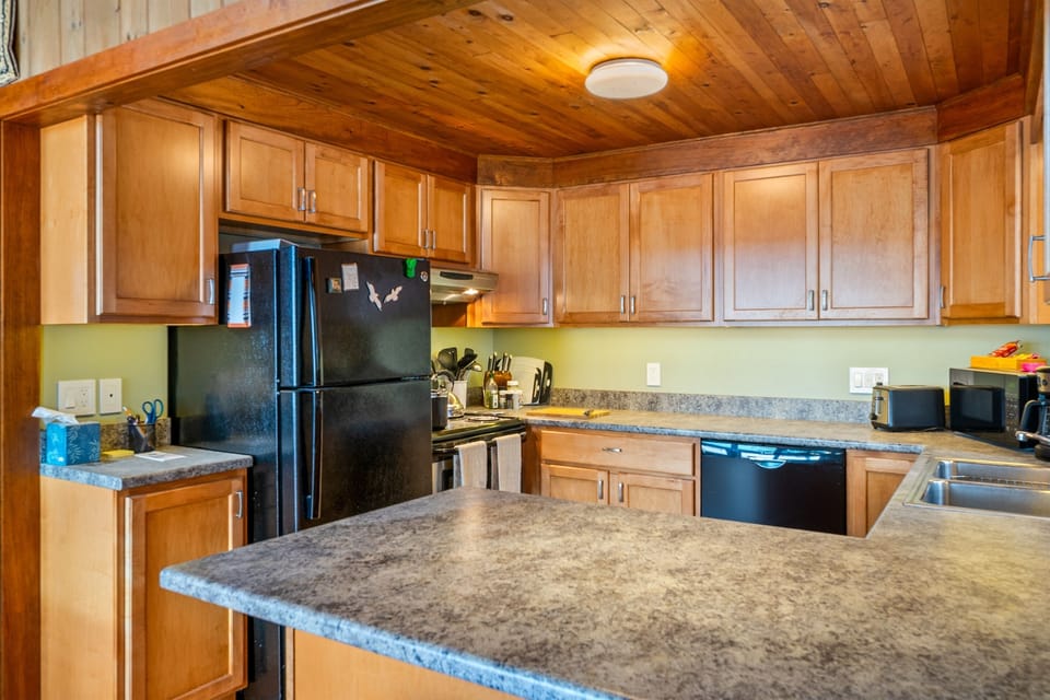 Traditional Maine charm. This well-provisioned kitchen features natural wood cabinetry and plenty of counter space for meal prep. Stocked with essentials for your stay, it’s a functional heart of the home on the Quiet Side near Acadia.