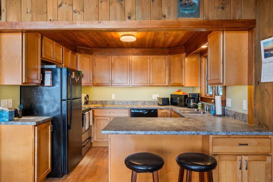 Traditional charm meets utility. This well-provisioned kitchen features natural wood cabinetry and a breakfast bar with seating for two. It’s the perfect spot for a quick trail breakfast before exploring Bass Harbor and Acadia.