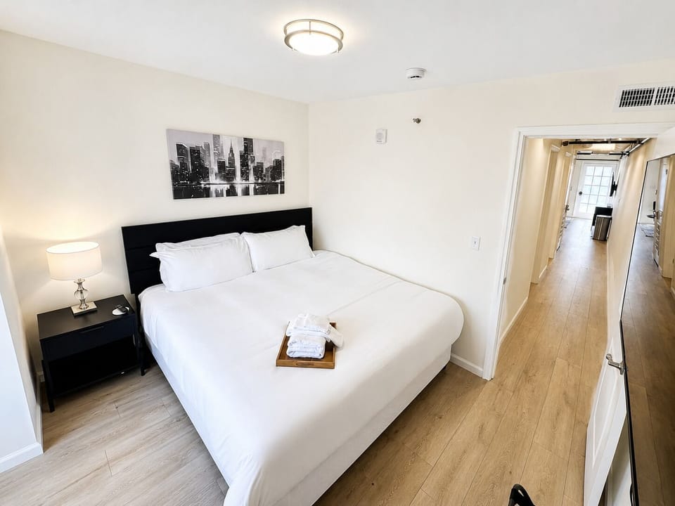 Alternate view of the first bedroom showing the prepared bed and connecting hallway.