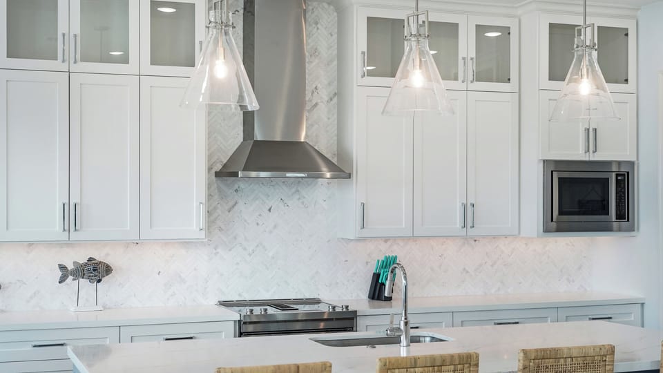 Elegant kitchen with custom cabinetry, marble backsplash, and stainless range hood in this upscale Galveston beach house rental.