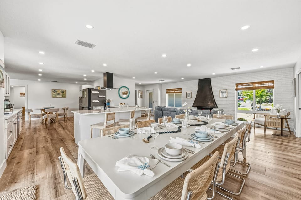 A large dining table sits beside the kitchen with bar seating for additional guests.