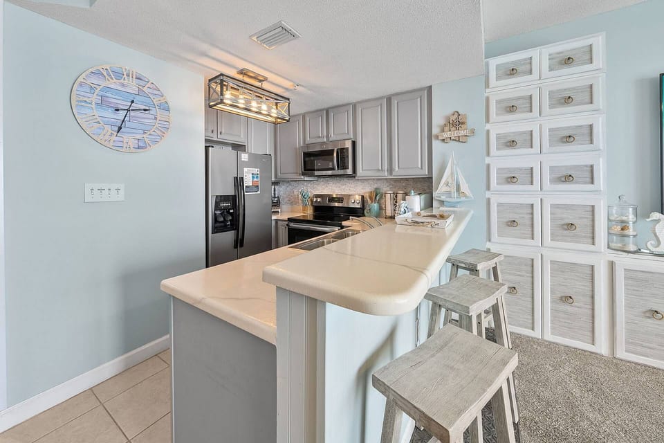 Updated kitchen with stainless steel appliances, quartz countertops, stone tile backsplash, and bar seating — fully equipped for your stay.