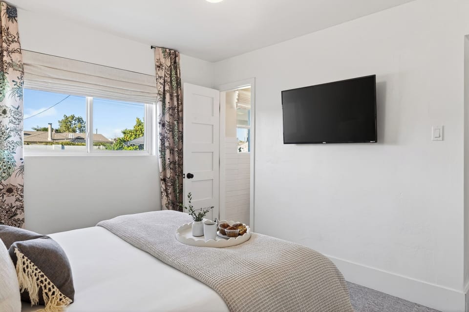 Minimalist bedroom design featuring a wall-mounted TV and natural light.