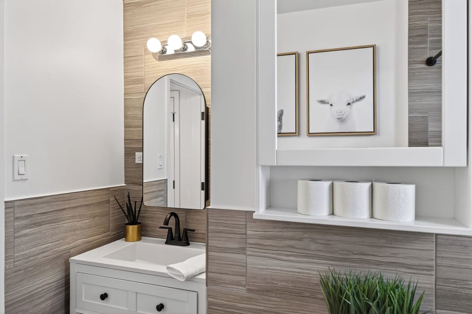 Sleek vanity with a round mirror and contemporary tile work.
