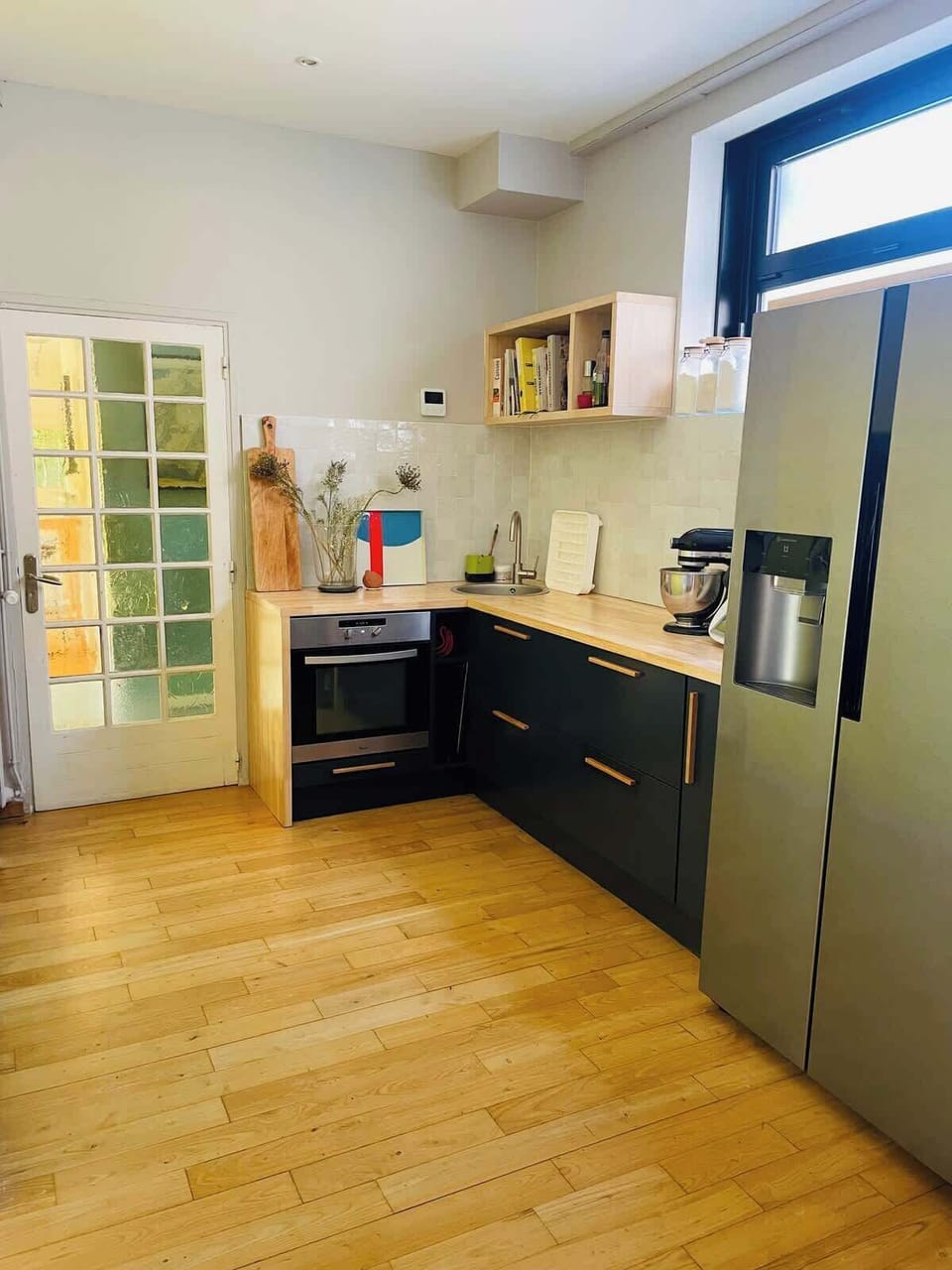 Cuisine équipée avec réfrigérateur-congélateur, meubles sombres et plan de travail en bois