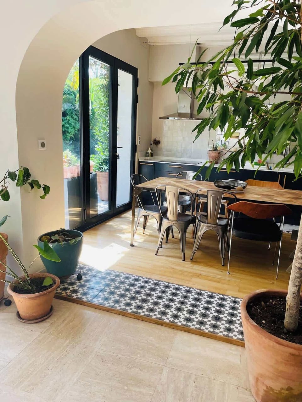 Espace repas lumineux avec verrière donnant sur le jardin et plantes vertes
