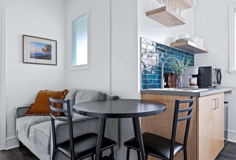 Enjoy a cozy dining space alongside a well-equipped kitchenette featuring a mini fridge, microwave, sink, and coffee maker — perfect for light meals, takeout nights, or morning coffee before exploring downtown Asheville.