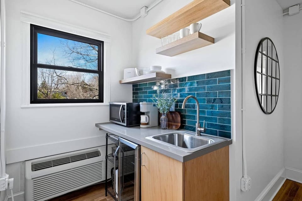 Enjoy the convenience of a well-equipped kitchenette featuring a mini fridge, microwave, sink, coffee maker, and open shelving — ideal for preparing light meals and morning coffee during your stay. Layout and shelving may vary slightly by unit.