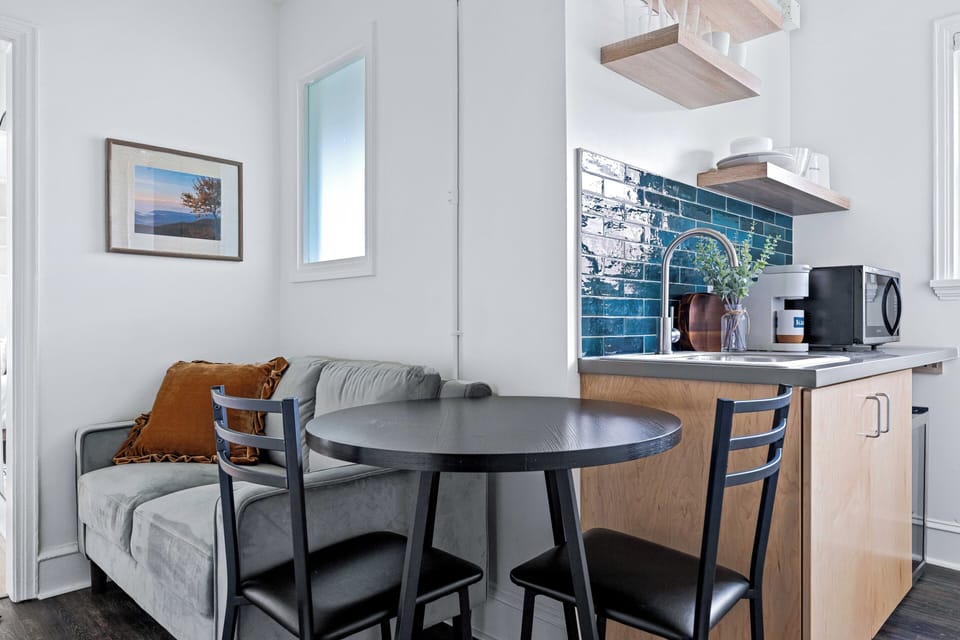 Enjoy a cozy dining space alongside a well-equipped kitchenette featuring a mini fridge, microwave, sink, and coffee maker — perfect for light meals, takeout nights, or morning coffee before exploring downtown Asheville.