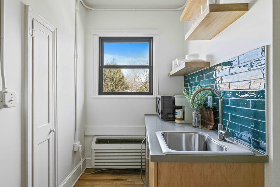 Enjoy the convenience of a well-equipped kitchenette featuring a mini fridge, microwave, sink, coffee maker, and open shelving — ideal for preparing light meals and morning coffee during your stay. Layout and shelving may vary slightly by unit.