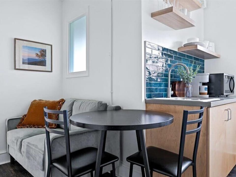 Enjoy a cozy dining space alongside a well-equipped kitchenette featuring a mini fridge, microwave, sink, and coffee maker — perfect for light meals, takeout nights, or morning coffee before exploring downtown Asheville.